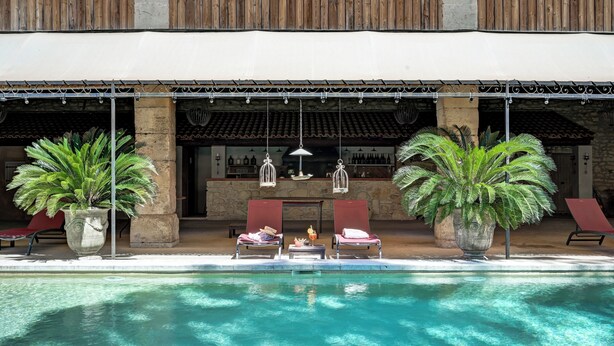 A poolside area with lounge chairs, a bar, and decorative lighting. - Mas des Comtes de Provence (Tarascon)