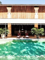Zona de piscina con sillas de descanso y plantas en macetas.