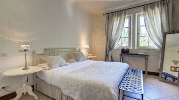 A bedroom with a bed, bedside table, lamp, and a mirror.