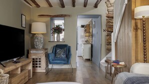 Un salon confortable avec un téléviseur, un fauteuil bleu et une table basse en bois.