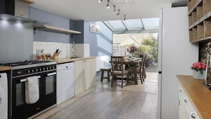 Une cuisine moderne équipée d’une cuisinière à gaz, d’un lave-vaisselle et d’un coin repas avec une table et des chaises.