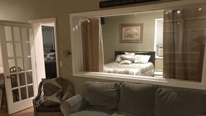 A room with a grey sofa, a wicker chair, a bed with a canopy, and a large mirror reflecting the room. - Songbrook + (Otego)