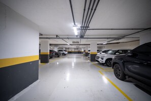 Un estacionamiento de varios niveles con paredes a rayas blancas y amarillas, varios coches estacionados y columnas estructurales visibles.