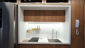 Una cocina moderna con armarios de madera, un refrigerador de acero inoxidable, un lavamanos y un teléfono montado en la pared.