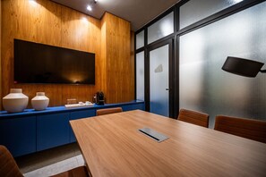 Una sala de conferencias con una mesa de madera, armarios azules y una pantalla grande.