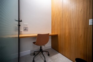 Oficina en esquina con escritorio de madera, silla giratoria y pared blanca con símbolo de Wi-Fi.