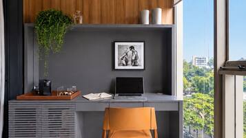 A modern office space with a desk, chair, and a view of the city through large windows.