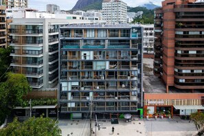 Un edificio de varios pisos con balcones, ventanas amplias y una terraza en la azotea.
