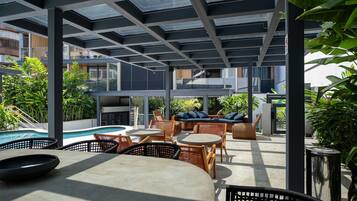 An outdoor patio area with seating, a pool, and a view of the surrounding buildings.