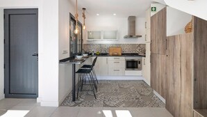 A modern kitchen with a bar area, a microwave, and a wooden cabinet. - Villa - Canas da Ria - Private Pool (Santa Luzia)