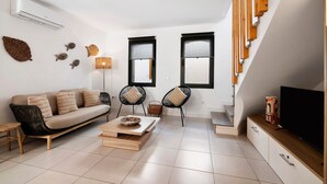 A modern living room with a sofa, chairs, a coffee table, a TV, and a staircase. - Villa - Canas da Ria - Private Pool (Santa Luzia)