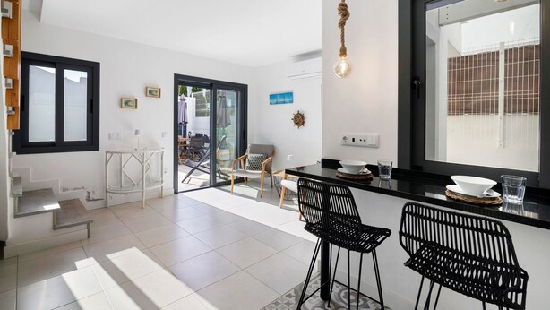 A modern kitchen with a dining area, a staircase, and a view through a glass door. - Villa - Canas da Ria - Private Pool (Santa Luzia)