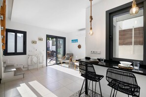 A modern kitchen with a dining area, a staircase, and a view through a glass door. - Villa - Canas da Ria - Private Pool (Santa Luzia)