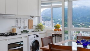 Een moderne keuken met witte kastjes, een inbouwoven, een wasmachine, en een eethoek met een tafel en stoelen.