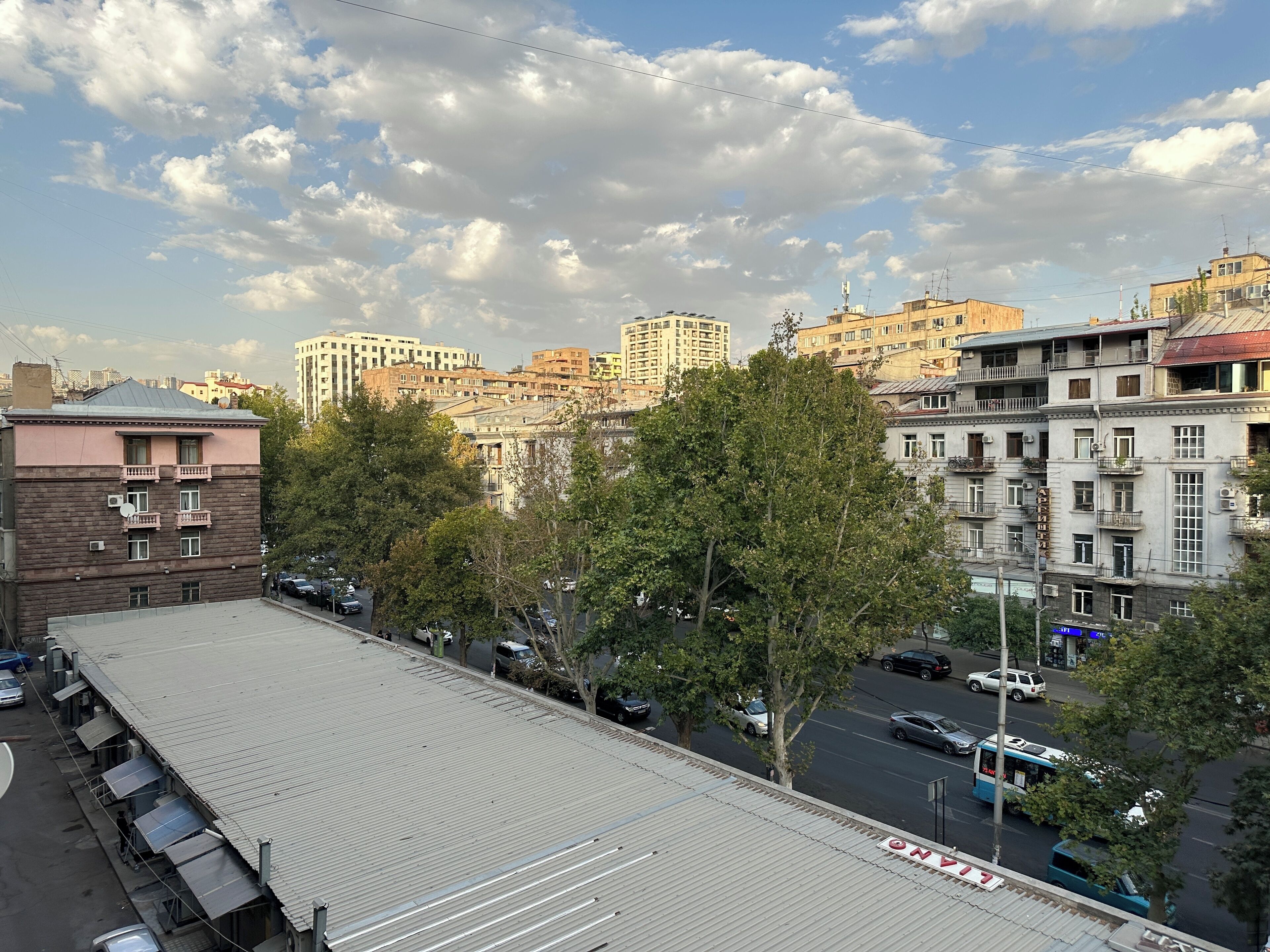 Un edificio de varios pisos con techo plano y varios balcones, con un estacionamiento al frente.