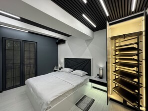 Une chambre à coucher moderne comprenant un lit, des tables de chevet, une armoire et une étagère intégrée.