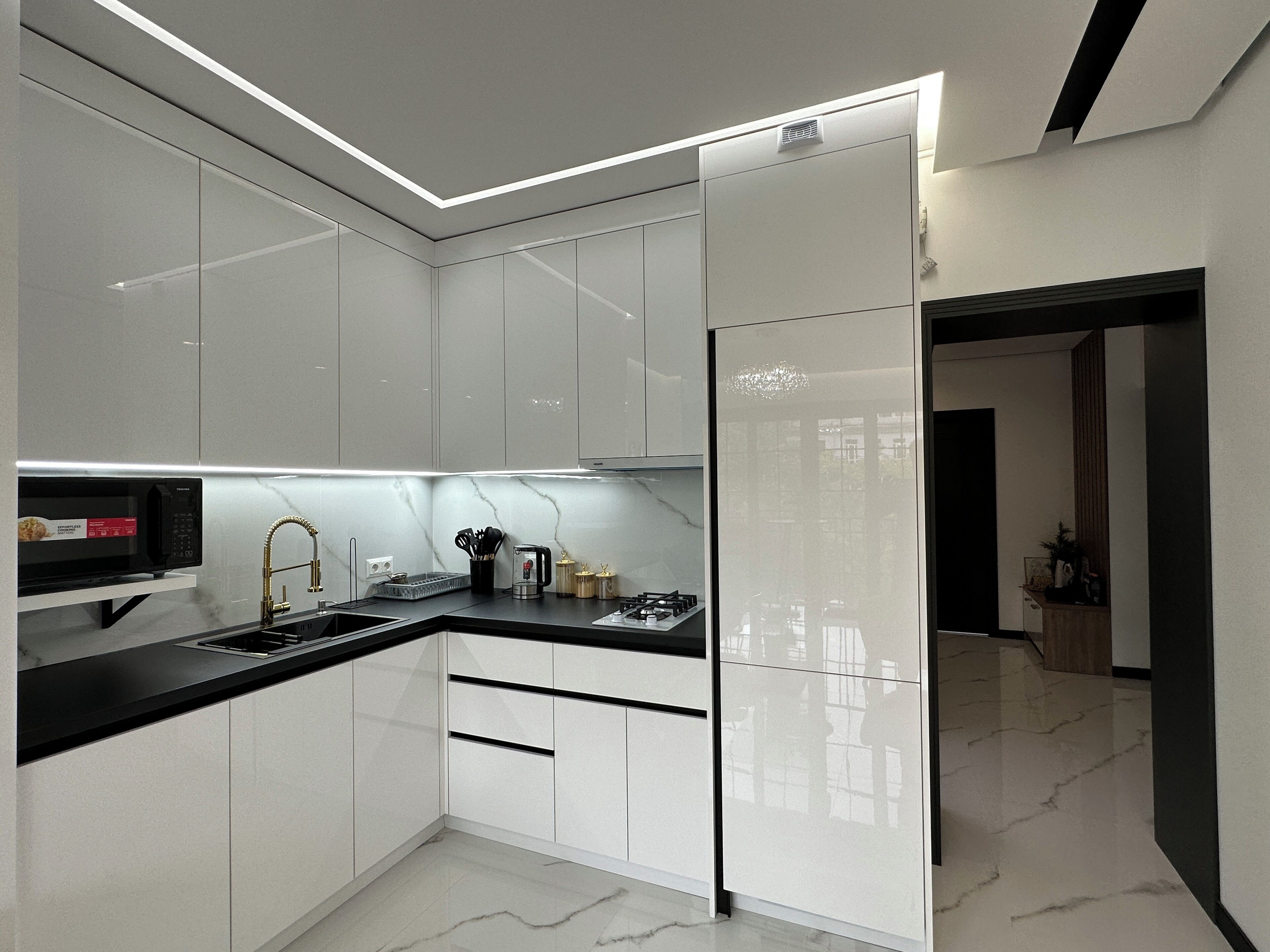 A modern kitchen with white cabinets, a black countertop, and a stainless steel range hood.