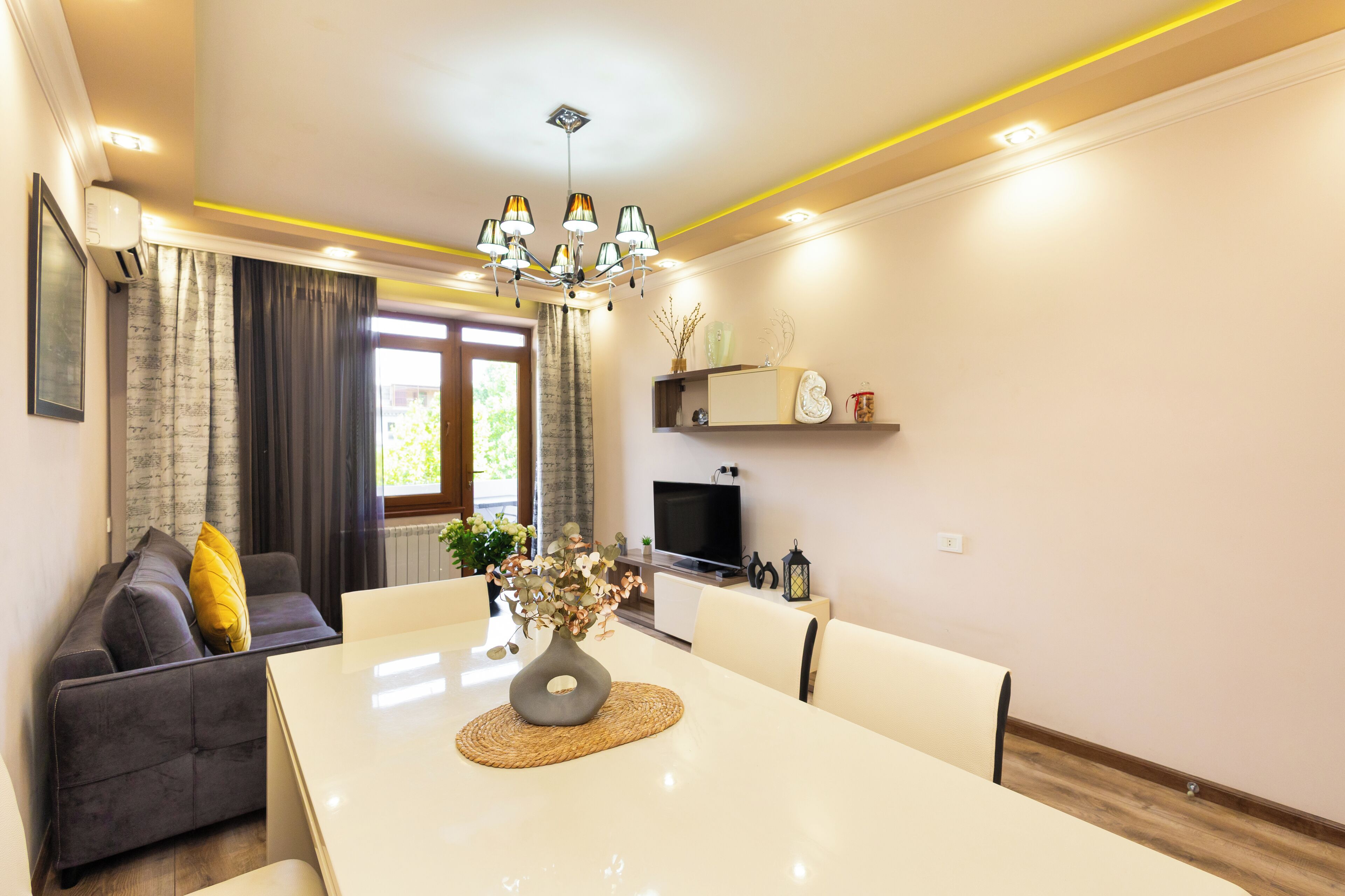Ein modernes Wohnzimmer mit Esstisch, Sofa und Fernseher.