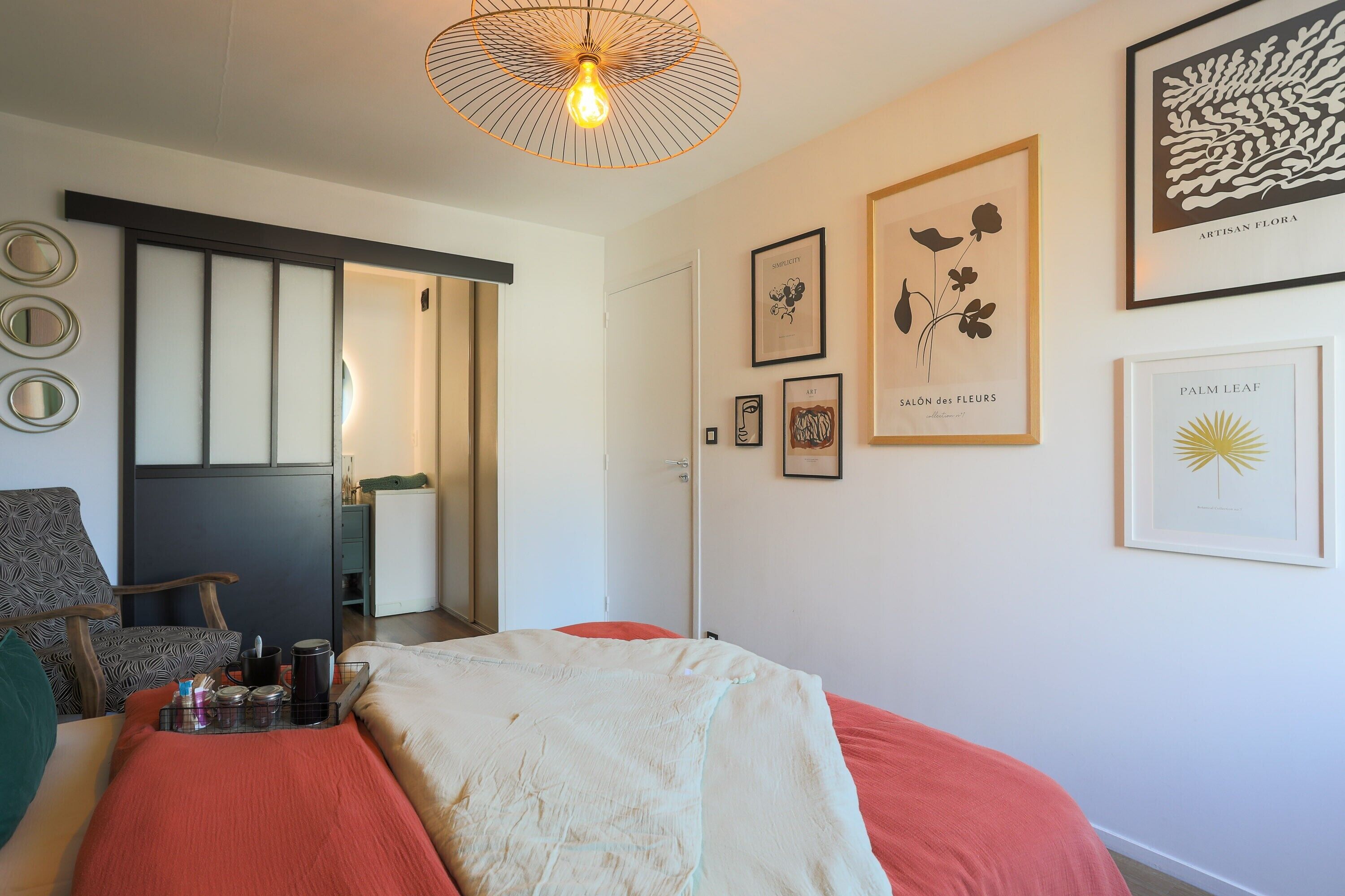 Une pièce comprenant un lit, une chaise, un bureau et un mur orné de tableaux.