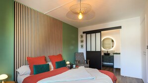 A modern bedroom with a large bed, bedside tables, a chair, a mirror, and a wardrobe. - "L'escale vers Bréhat" in Paimpol – Renovated Apartment in Port District (Paimpol)