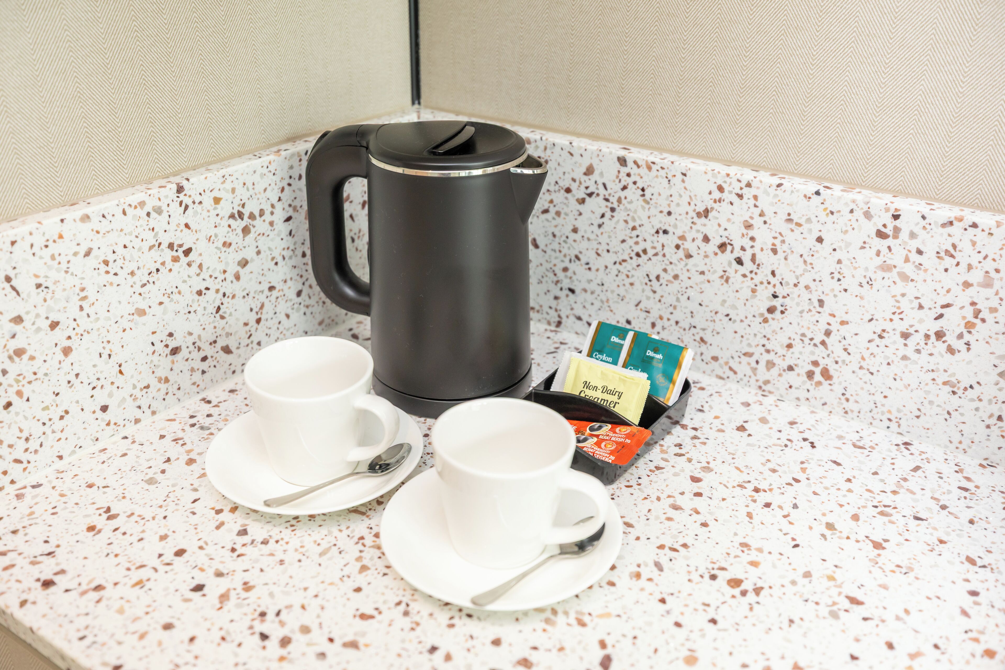 A kitchenette with a coffee maker, two cups, and a box of non-dairy creamer.