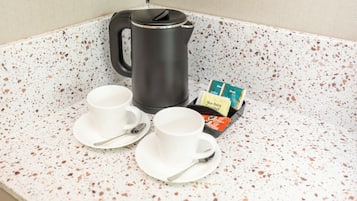 Eine Küchenzeile mit Kaffeemaschine, zwei Tassen und einer Packung laktosefreier Milch.