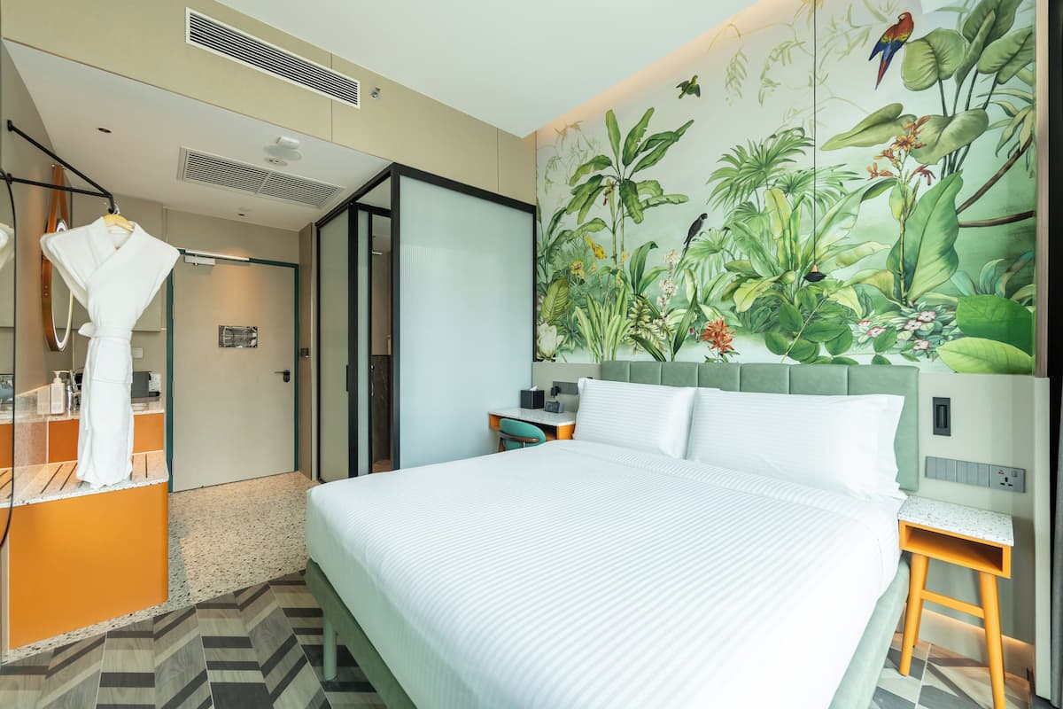 Une chambre d’hôtel avec un grand lit, un bureau, une chaise et une salle de bain équipée d’un miroir et d’un porte-serviettes.