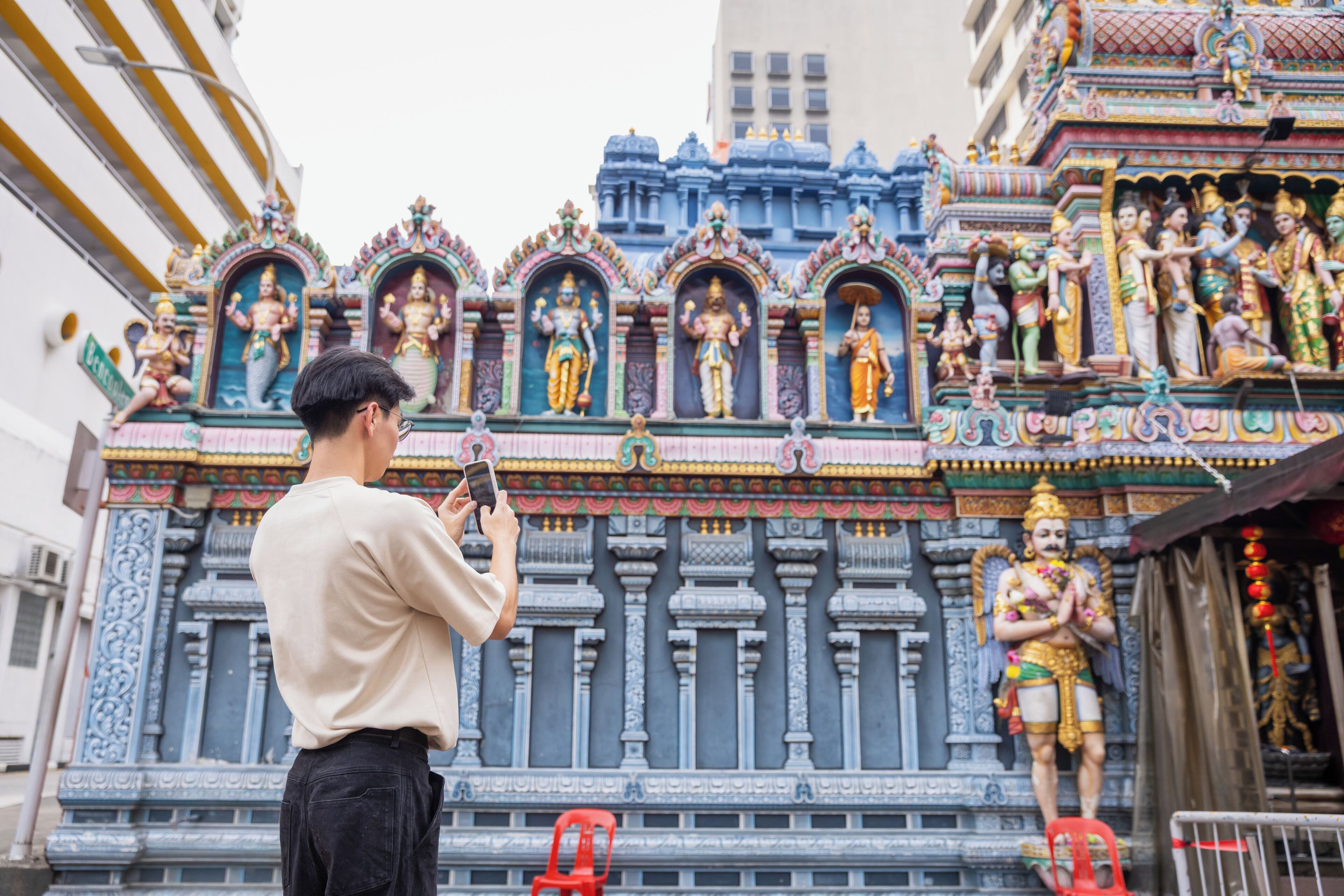 A person taking a photo of a temple with intricate carvings and statues.