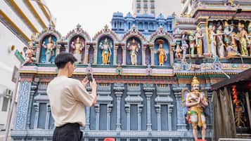 A person taking a photo of a temple with intricate carvings and statues.