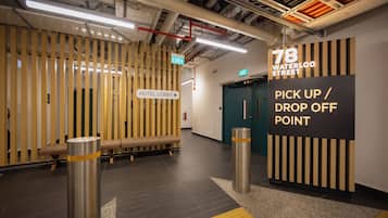 A hotel lobby with a wooden slat wall, a bench, a sign for the hotel lobby, and a pick-up/drop-off point sign.