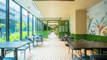 Un restaurante moderno con una distribución alargada y estrecha, paredes verdes y un suelo estampado.