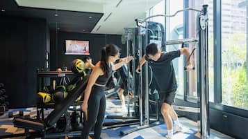 A gym with exercise equipment, a mirrored wall, and a large window.