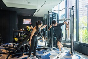 A gym with exercise equipment, a mirrored wall, and a large window.