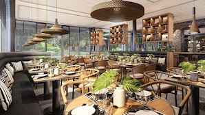 A modern restaurant interior with high ceilings, large windows, and a variety of seating arrangements including tables and booths. - Kamaliss MontAzure Phuket - MGallery Collection (Kamala)