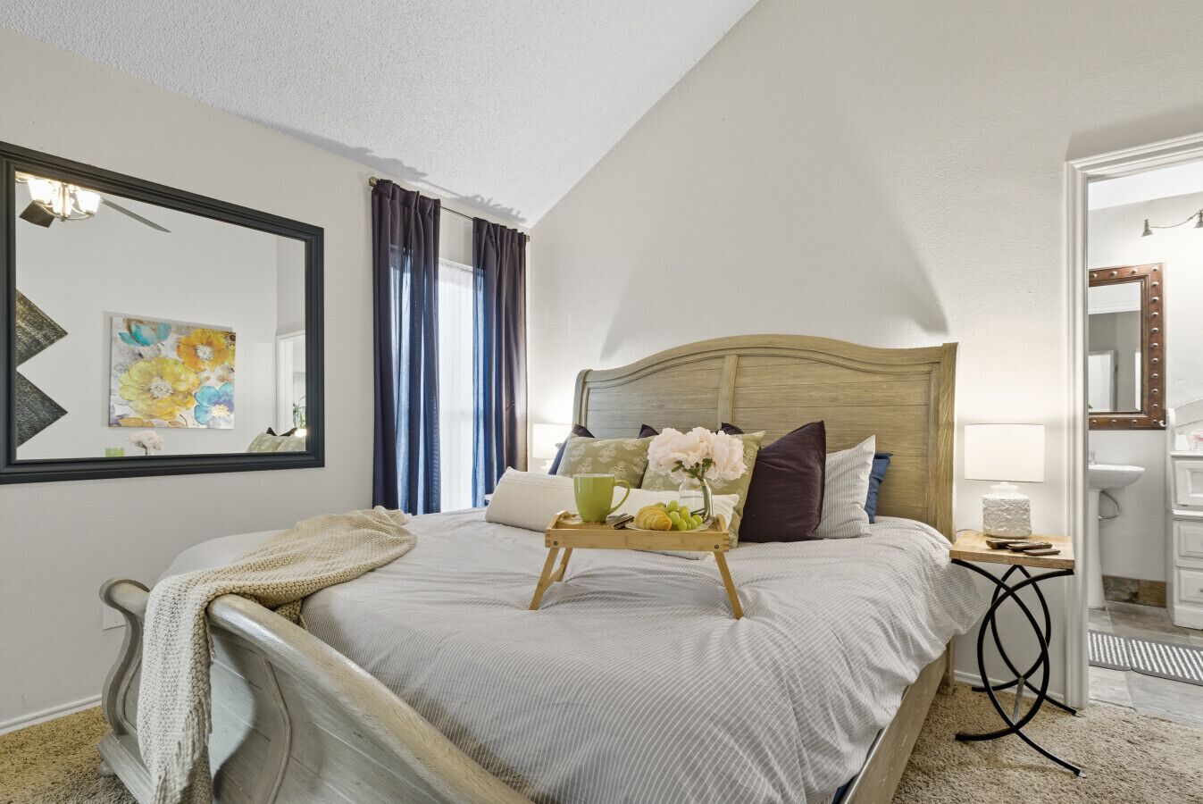 Une chambre bien rangée, avec un lit, une table de chevet et un miroir.