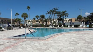 Una piscina amb gandules i palmeres, envoltada d'edificis.