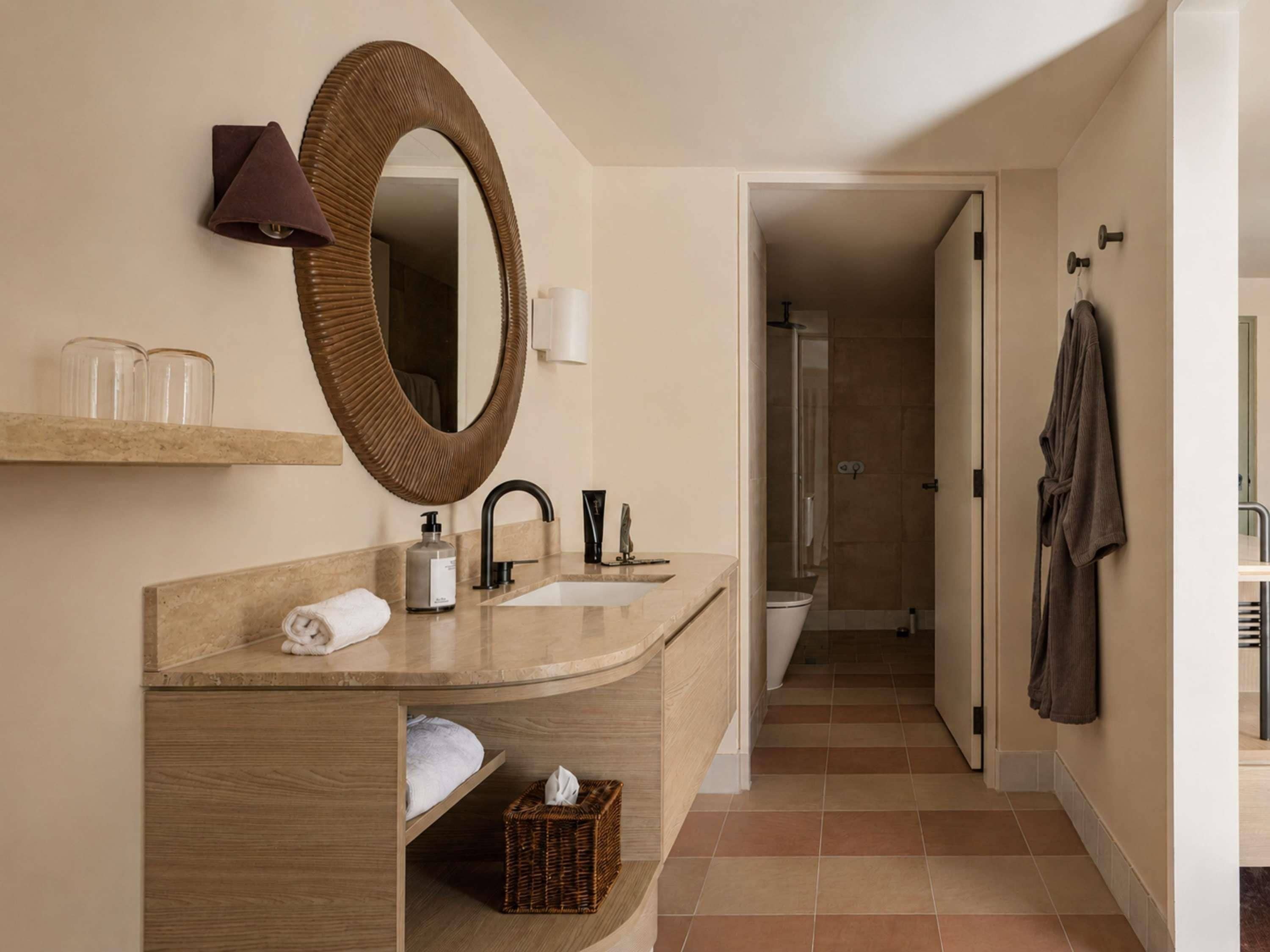 A modern bathroom with a large mirror, a sink, a towel, a bottle, and a shower area.