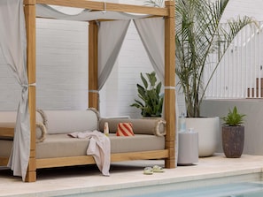 A wooden canopy bed with a beige mattress, a white curtain, and a pair of slippers on the floor. - Hyde Perth (Perth)