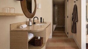 Een moderne badkamer met een grote spiegel, een wastafel, een handdoek, een fles en een douchehoek.