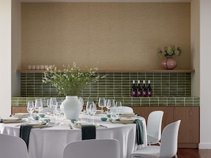 A dining area with a table set for four, a vase with flowers, and wine bottles on the wall. - Hyde Perth (Perth)