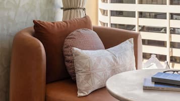 A brown leather sofa with patterned cushions, a round marble table, and a book titled 'The Paris Review.'