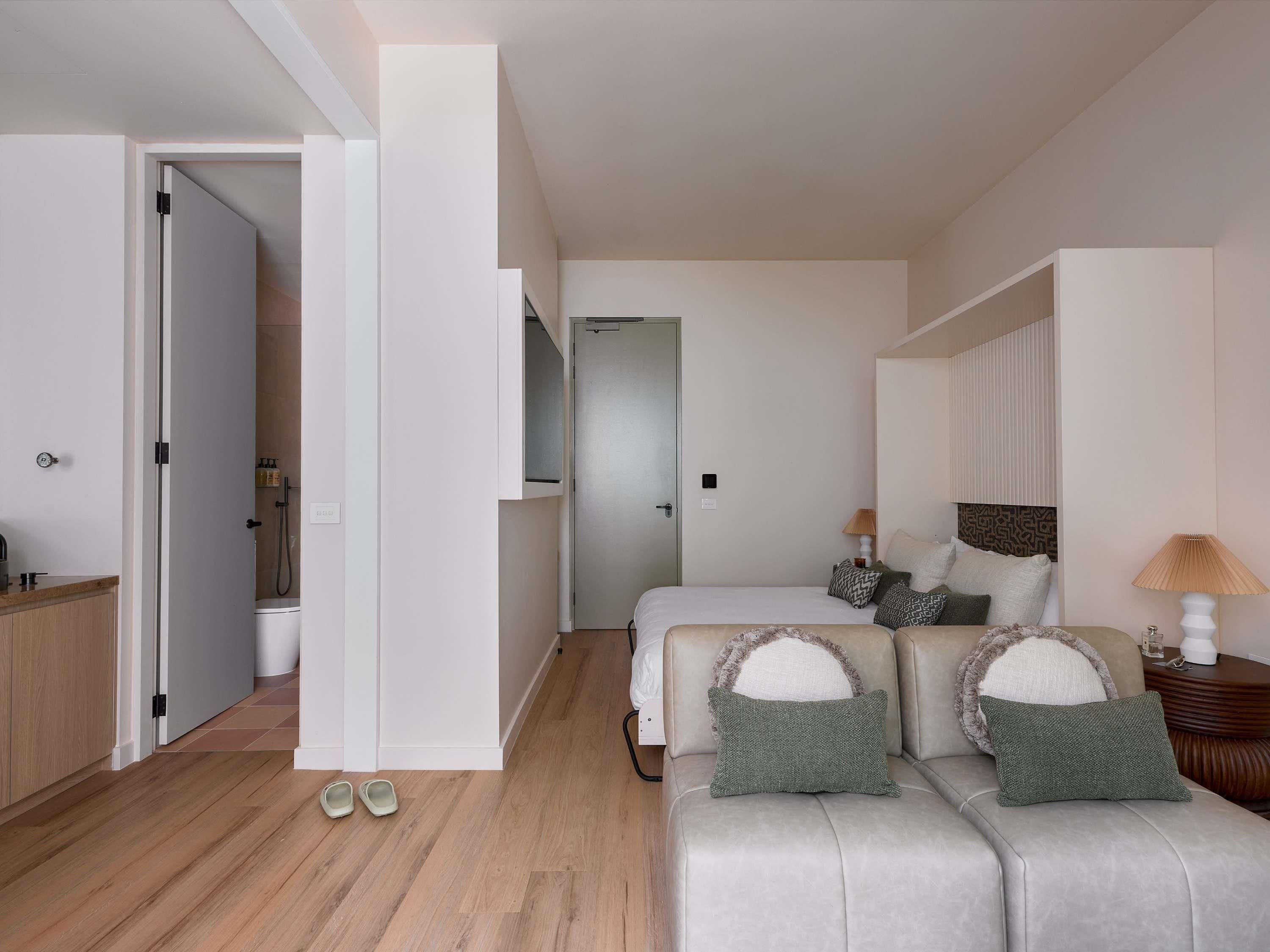 Un dormitorio moderno con cama, sofá y mesita de noche.