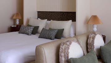 Habitació d'hotel amb llit, sofà, almoinades estampades i dues làmpades laterals.