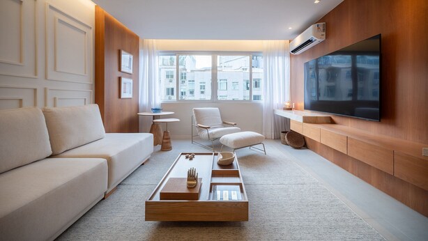 Ein modernes Wohnzimmer mit Sofa, Couchtisch, Fernseher und Blick auf Gebäude.