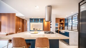 Eine moderne Küche mit einer zentralen Kochinsel, Barhocker und einer Edelstahl-Dunstabzugshaube.