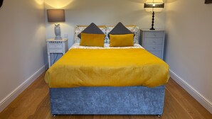 A neatly made bed with a yellow and gray duvet, flanked by two bedside tables with lamps, one of which has a decorative owl figurine. - Gosfield Cartlodge Retreat (Halstead)