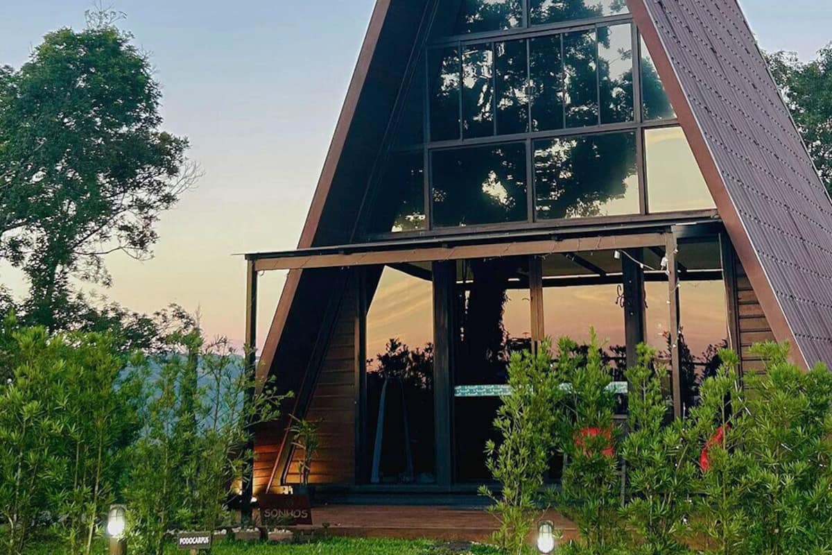 A modern, triangular-shaped building with large glass windows and a wooden exterior.