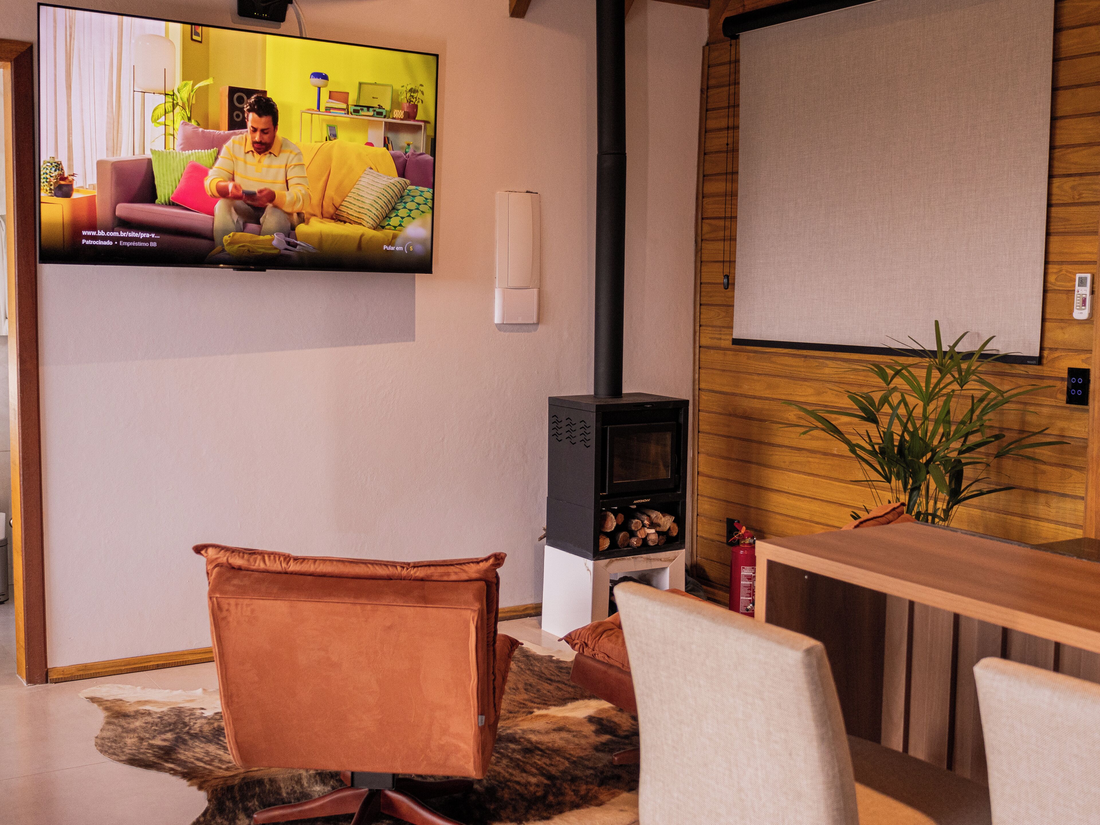 Een woonkamer met een aan de muur bevestigde televisie, een open haard en een bank.