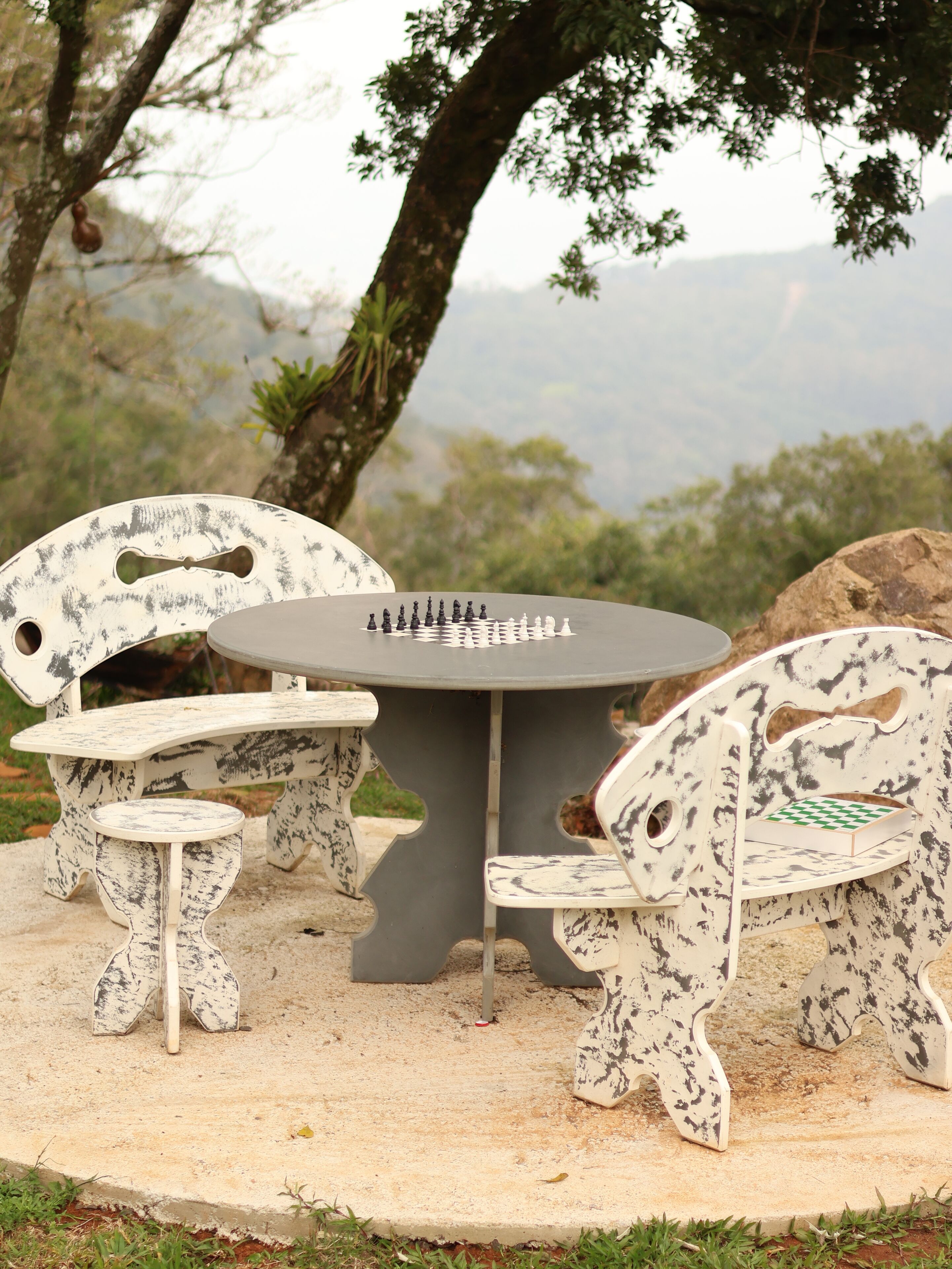 A chess table set outdoors with a view of trees and mountains in the background.