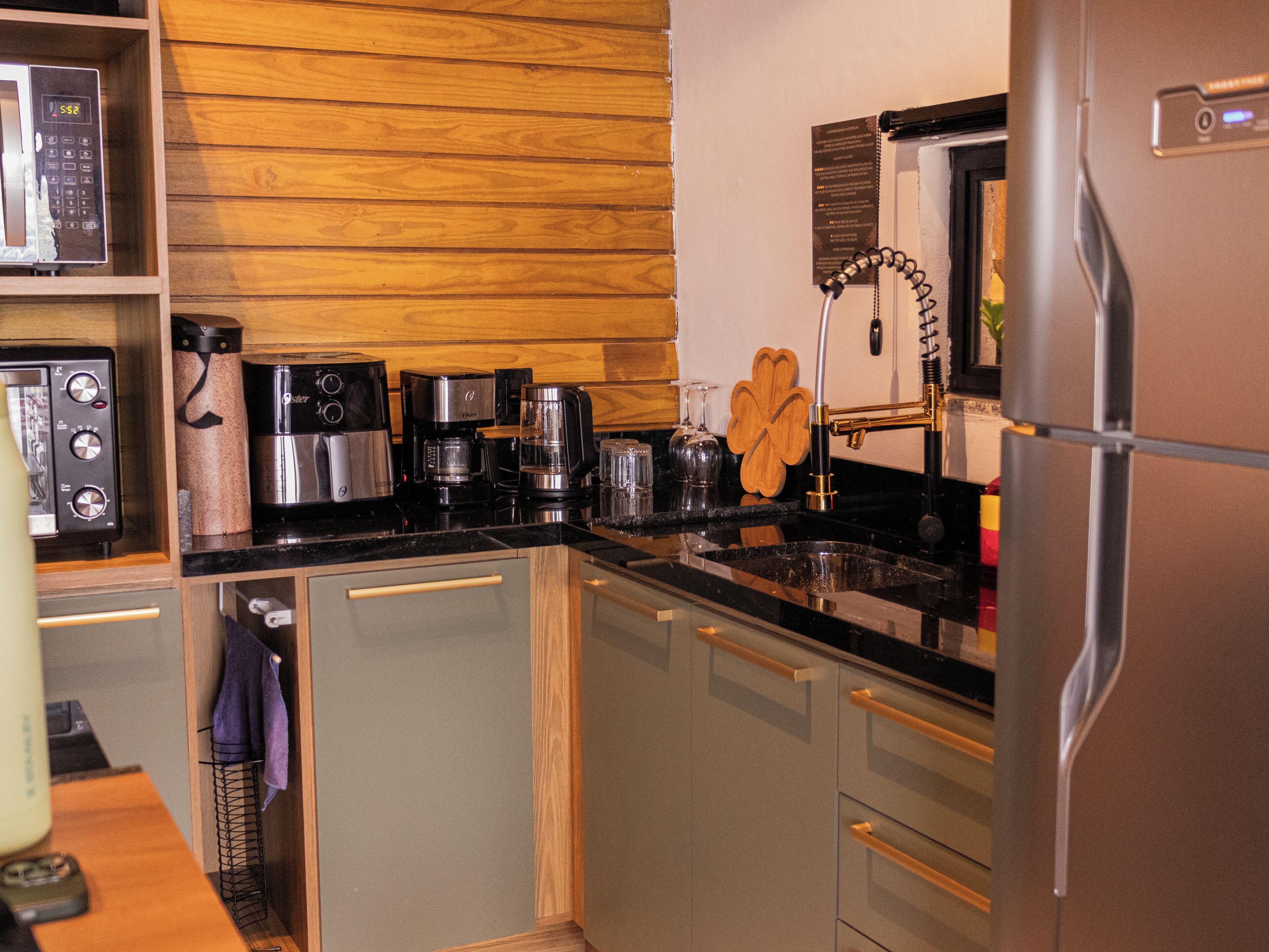 A compact kitchen with modern appliances, wooden wall paneling, and a stainless steel refrigerator.
